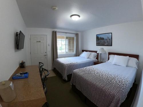 um quarto de hotel com duas camas e uma mesa em Col-Pacific Motel em Ilwaco