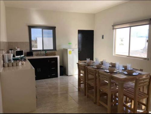 a dining room with a table and a kitchen with a refrigerator at Terra Viva Villa Campestre in Cuatrociénegas de Carranza