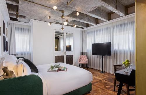 a bedroom with a white bed and a tv at Brown BoBo, a member of Brown Hotels in Tel Aviv
