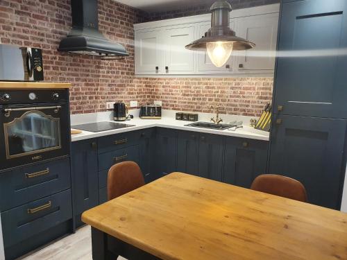 eine Küche mit blauen Schränken und einem Holztisch in der Unterkunft The Snug Bourne in Bourne