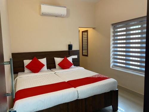 a bedroom with a large bed with red pillows at La Mer Inn in Kozhikode