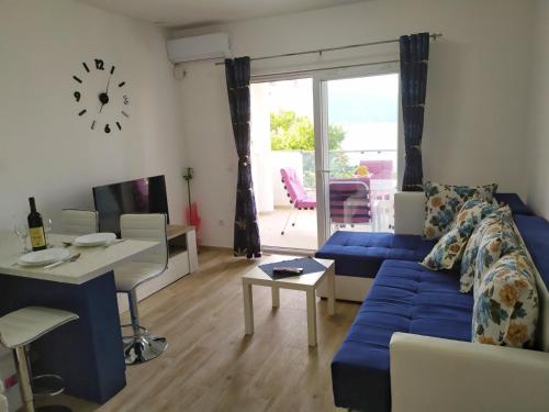 a living room with a blue couch and a table at Apartmani M&E in Tivat