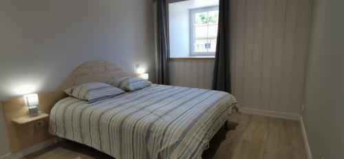 1 dormitorio con cama con colcha a rayas y ventana en Les perles vertes, en Arlempdes