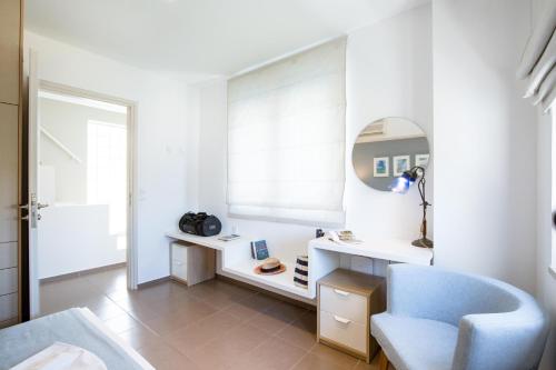 a white room with a blue chair and a mirror at Anna Plakias Apartments in Plakias