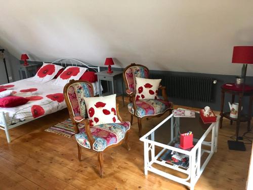 a bedroom with a bed and two chairs and a table at Les Coquelicots in Saint-Urbain