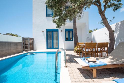 a pool with a table and chairs next to a house at Anna Plakias Apartments in Plakias