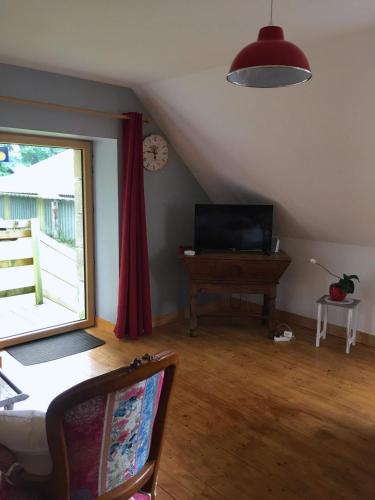 a living room with a table and a television and a window at Les Coquelicots in Saint-Urbain
