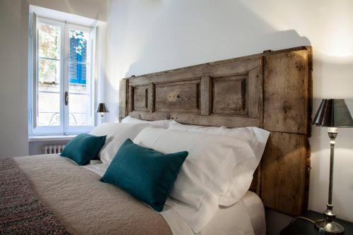 een bed met witte kussens en een houten hoofdeinde bij Casa Fabbrini Boutique B&B in Rome