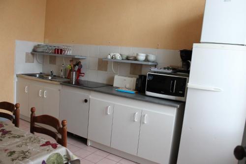 une cuisine avec des armoires blanches et un réfrigérateur blanc dans l'établissement COSY, à Rochefort