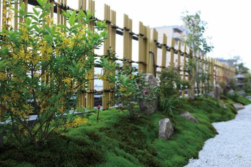 a fence next to a building with some plants at Matsui-Bekkan Hanakanzashi in Kyoto
