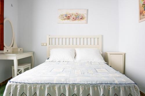 a white bedroom with a bed and a table at Casa Boutique Margarita in Peniscola
