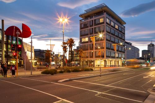 a city street with a tall building at night at The Muse Christchurch Art Hotel in Christchurch