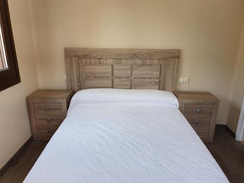 a bedroom with a white bed and two wooden dressers at Casas Fontan in Combarro