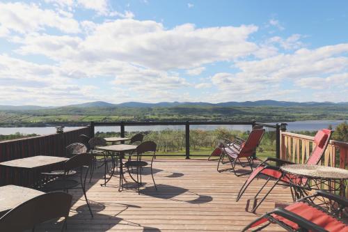 a deck with tables and chairs and a view of a lake at Domaine Steinbach Cidrerie B&B Distillerie in St-Pierre-de-l'Île-d'Orléans