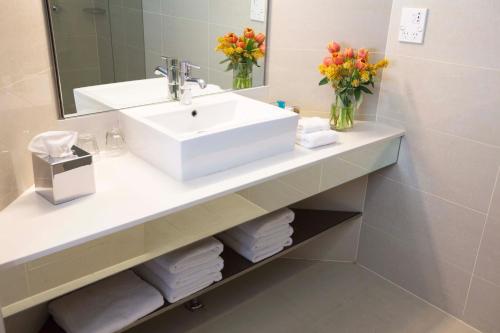 a bathroom with a sink and a mirror and flowers at Novotel Sydney Olympic Park in Sydney