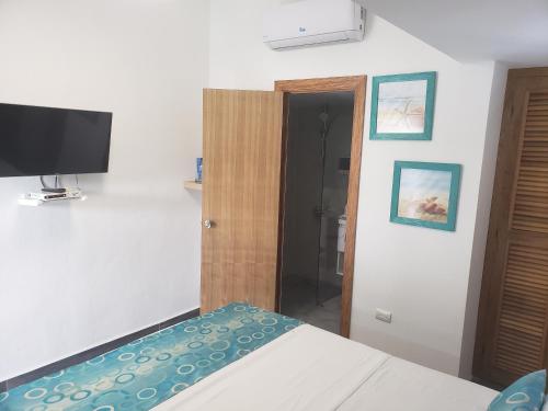 a bedroom with a bed and a flat screen tv at Hotel Agua Dulce in Boca Chica