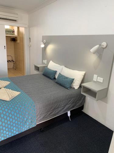 a bedroom with a bed with blue and white pillows at Glen Innes Motel in Glen Innes