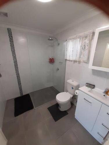a bathroom with a toilet and a shower and a sink at Casuarina Studio in Yeppoon