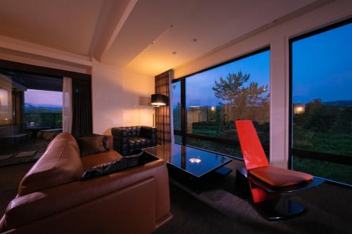 a living room with a couch and a chair and large windows at Riverte Kyoto Kamogawa in Kyoto