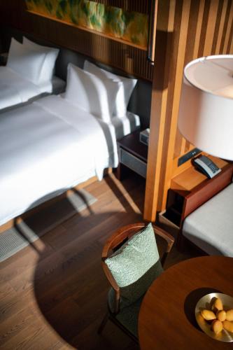 a hotel room with a bed and a table and a chair at New World Qingyuan Hotel -formerly KHOS QINGYUAN in Qingyuan
