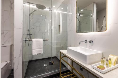 a bathroom with a sink and a shower at The Muse Christchurch Art Hotel in Christchurch