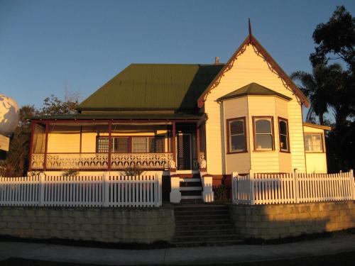 a yellow house with a white fence in front of it at Port Macquarie Backpackers in Port Macquarie