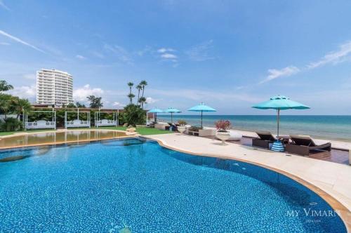 a swimming pool with chairs and umbrellas next to the ocean at My Resort@HUA HIN A504 in Hua Hin