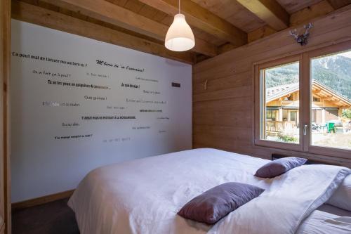 - une chambre avec un lit blanc et un mur avec un menu dans l'établissement Grand chalet Le Trappeur - Chamonix, à Chamonix-Mont-Blanc