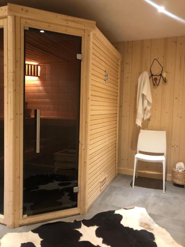 Cette chambre dispose d'une porte coulissante en verre avec une chaise. dans l'établissement Grand chalet Le Trappeur - Chamonix, à Chamonix-Mont-Blanc