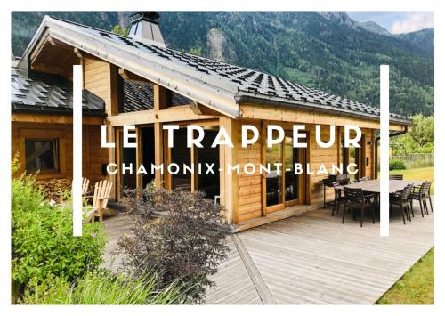 a building with a wooden deck with a table at Grand chalet Le Trappeur - Chamonix in Chamonix-Mont-Blanc