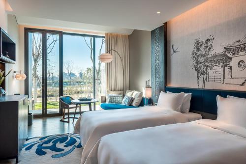 een hotelkamer met twee bedden en een raam bij Pullman Kaifeng Jianye in Kaifeng