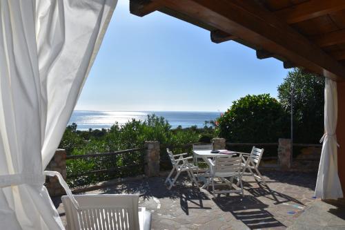 um pátio com uma mesa e cadeiras e o oceano em Domus Deborah Apartment with sea view Costa rei em Costa Rei