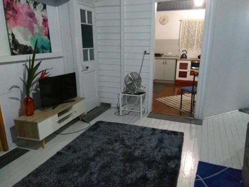 a living room with a television and a kitchen at Spacious Townsville City Apartment in Townsville