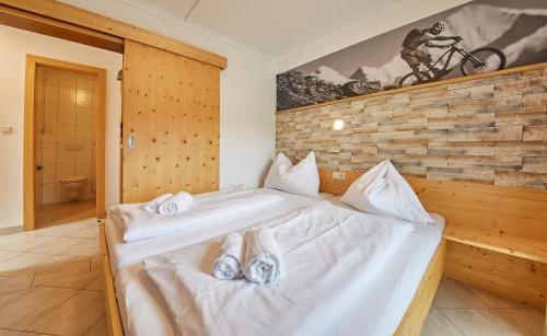 a bedroom with a bed with white sheets at Ski & Bike Appartements Forsthaus in Saalbach Hinterglemm