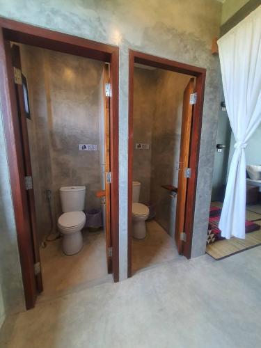 a bathroom with two toilets and two open doors at Le Cocotier in Ban Cho Lae