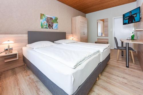 Cama blanca grande en habitación con mesa en Pension Nordlicht, en Esens