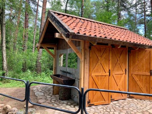 a wooden shed with a trash can in the woods at Caravana Juliana Hobby 545 z widokiem na Jezioro in Swaderki