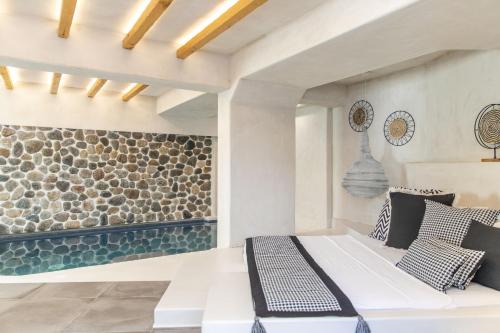 a bedroom with a white bed and a stone wall at Korali Palace Hotel in Naxos Chora