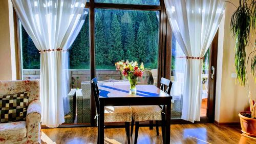 uma sala de jantar com uma mesa e uma grande janela em Carpatica Lodge em Moieciu de Sus