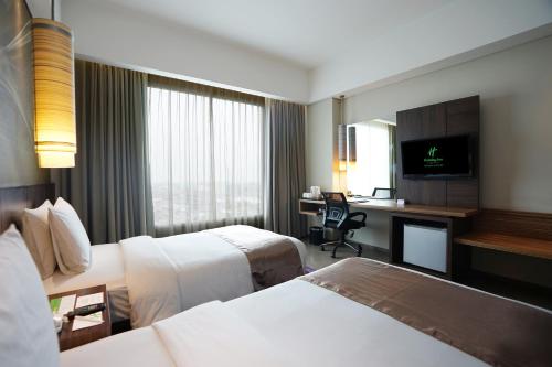 a hotel room with two beds and a desk at Holiday Inn Bandung Pasteur by IHG in Bandung