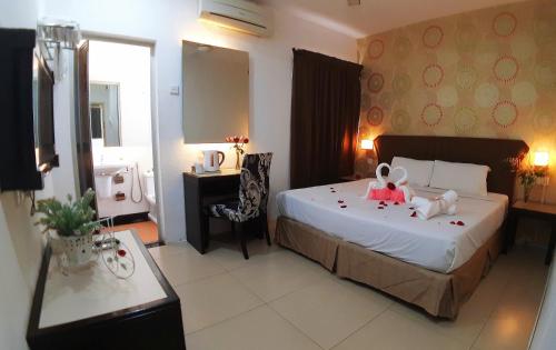 a bedroom with a bed with two stuffed animals on it at Quality Guest House in Kuantan