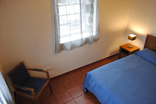 a bedroom with a bed and a chair and a window at Casas Da Faja in Praia do Norte