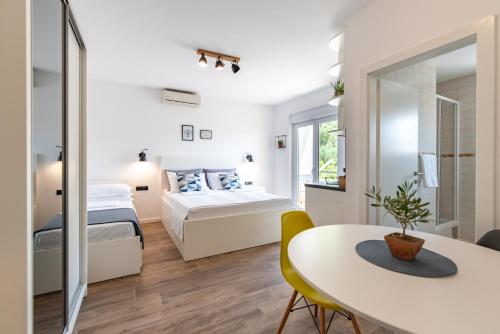 a bedroom with a bed and a table and a bed and a mirror at Maslina Apartments in Krvavica