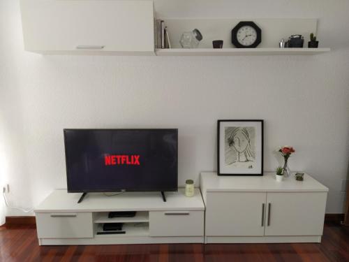 una sala de estar con TV en un centro de entretenimiento blanco en Duplex de 130m2 al lado de las playas de Cuchia, en Miengo