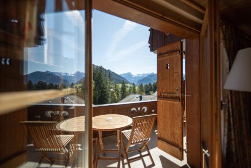 einen Blick vom Balkon eines Hauses mit einem Tisch und Stühlen in der Unterkunft Hotel Alpenrose mit Gourmet-Restaurant Azalée in Gstaad