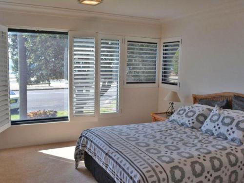 a bedroom with a bed and windows with shutters at Florentine 4 spectacular views and air conditioning in Nelson Bay