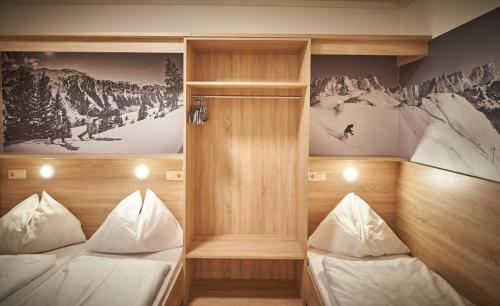 two beds in a room with mountains on the walls at Ski & Bike Appartements Forsthaus in Saalbach Hinterglemm