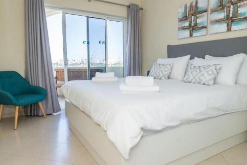 a bedroom with a large white bed with a window at One Bedroom Sea View Apartment Clube Rio Ferragudo in Ferragudo