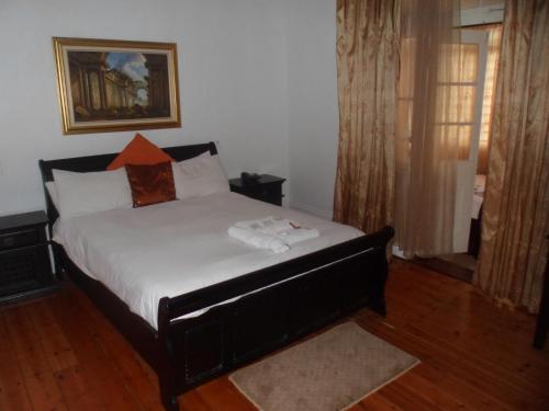 a bedroom with a large bed with white sheets at Laletsa Lodge in Durban