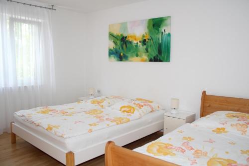 a bedroom with two beds and a painting on the wall at FeWo Bayha "Im Ort" in Langenargen